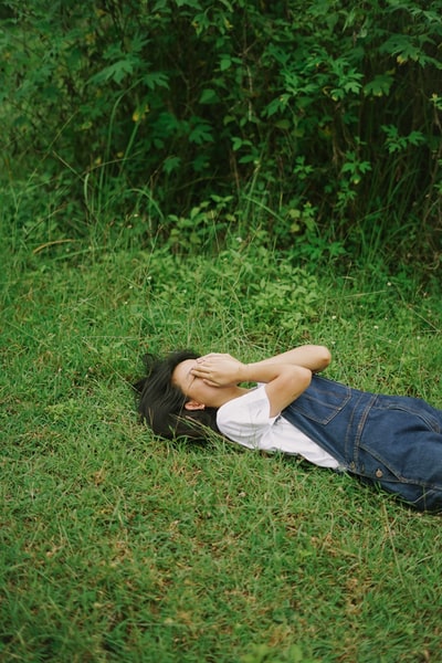 女人白衬衣躺在绿色的草地
